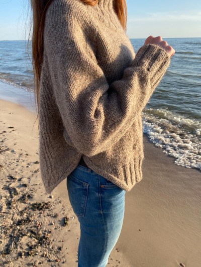 Side view of beige Yoga Winter sweater showing elegant side slits by the sea