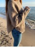 Side view of beige Yoga Winter sweater showing elegant side slits by the sea
