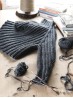 Dark grey Midnight jumper knitting pattern shown in progress on a wooden table with one sleeve on needles.