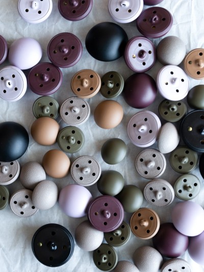 Flat lay of matte metal domed shank-back buttons in lavender, plum, olive, sand, stone and black