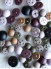 Flat lay of matte metal domed shank-back buttons in lavender, plum, olive, sand, stone and black