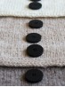 Close-up of Ruke black 28 mm four-hole bioresin buttons on beige knit