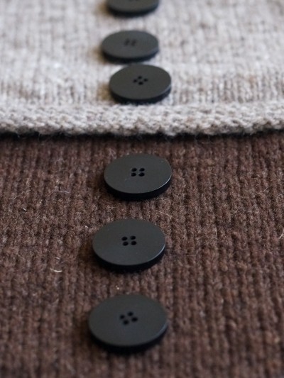 Close-up of Ruke black 28 mm four-hole bioresin buttons on brown knit