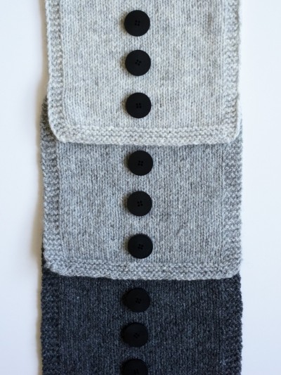 Ruke black 28 mm four-hole bioresin buttons on grey knitted swatches