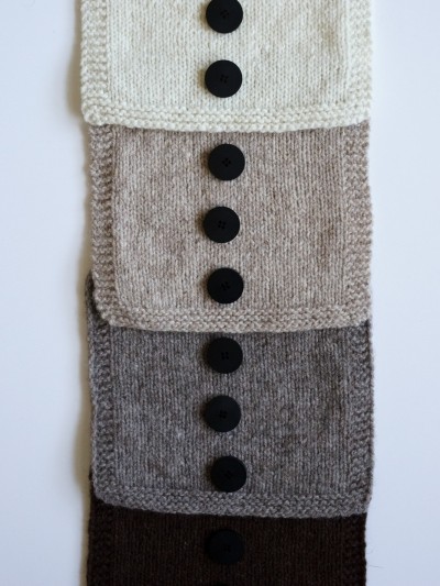 Ruke black 28 mm four-hole bioresin buttons on layered knit swatches