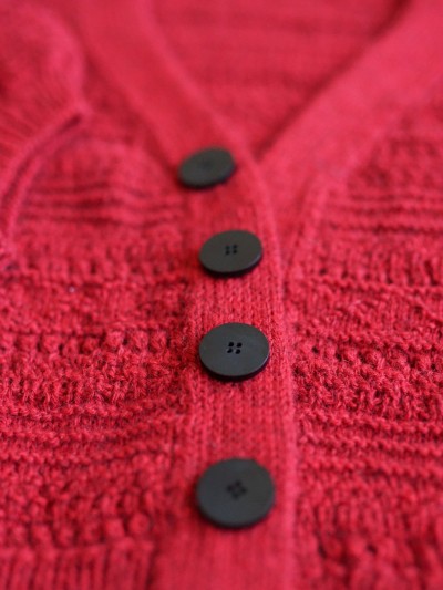 Ruke black 28 mm four-hole bioresin buttons on a red knit cardigan detail