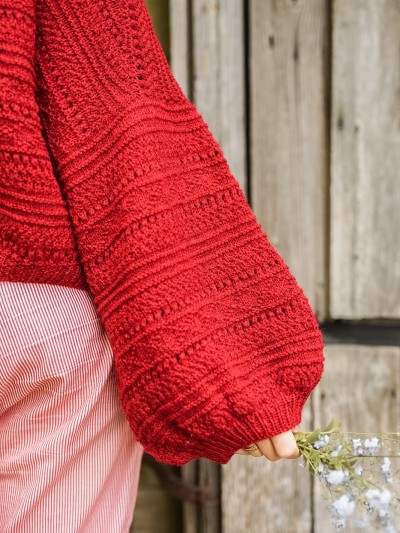 Close-up of the red Ruke Moon cardigan knitting pattern balloon sleeve and textured stitches
