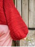 Close-up of the red Ruke Moon cardigan knitting pattern balloon sleeve and textured stitches