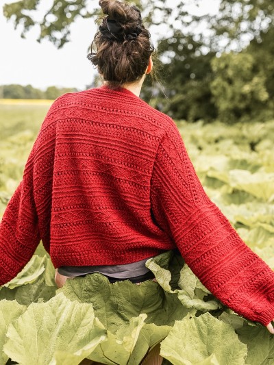 Back view of the red Ruke Moon cardigan knitting pattern with textured stitch panels