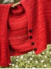 Red Ruke Moon cardigan knitting pattern hanging outdoors with black buttons and flower meadow