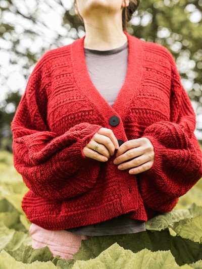 Model wearing the red Ruke Moon cardigan knitting pattern, front view with oversized sleeves