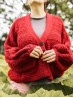 Model wearing the red Ruke Moon cardigan knitting pattern, front view with oversized sleeves