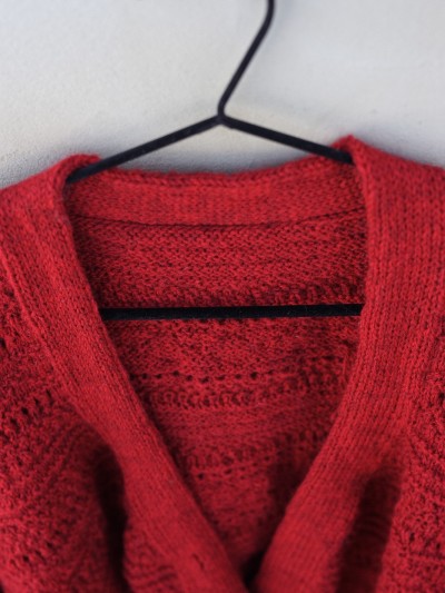 Close-up of the neckline and textured yoke on the red Ruke Moon cardigan knitting pattern