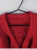 Close-up of the neckline and textured yoke on the red Ruke Moon cardigan knitting pattern