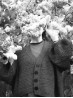 Black and white portrait of a model wearing the Ruke Moon cardigan knitting pattern among lilacs