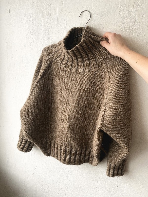 Knitted brown Yoga Winter sweater held by hand showing front view Knitted brown Yoga Winter sweater held by hand showing front view